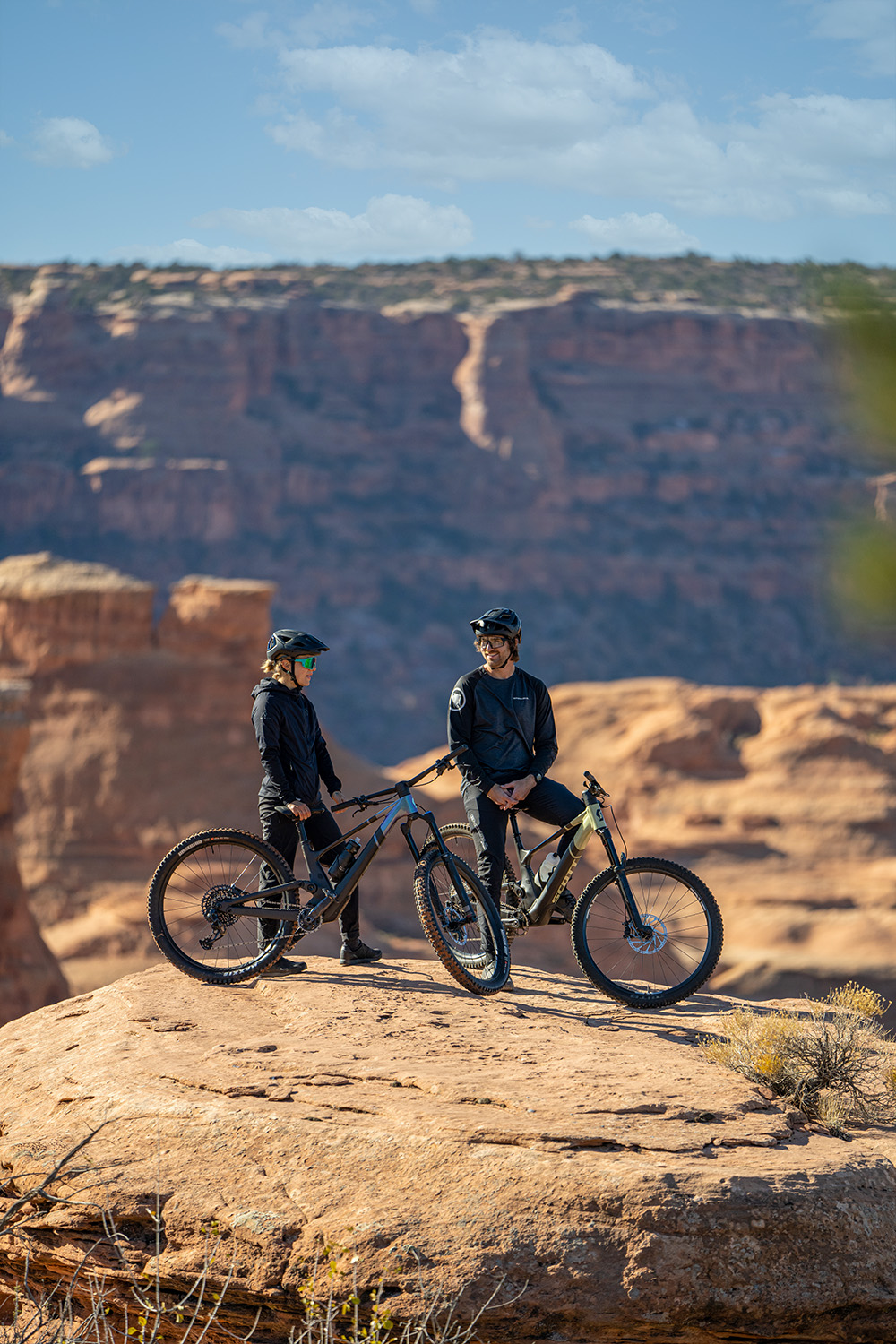 Eric and Libby standing over their bikes on a rock overlooking a canyon.