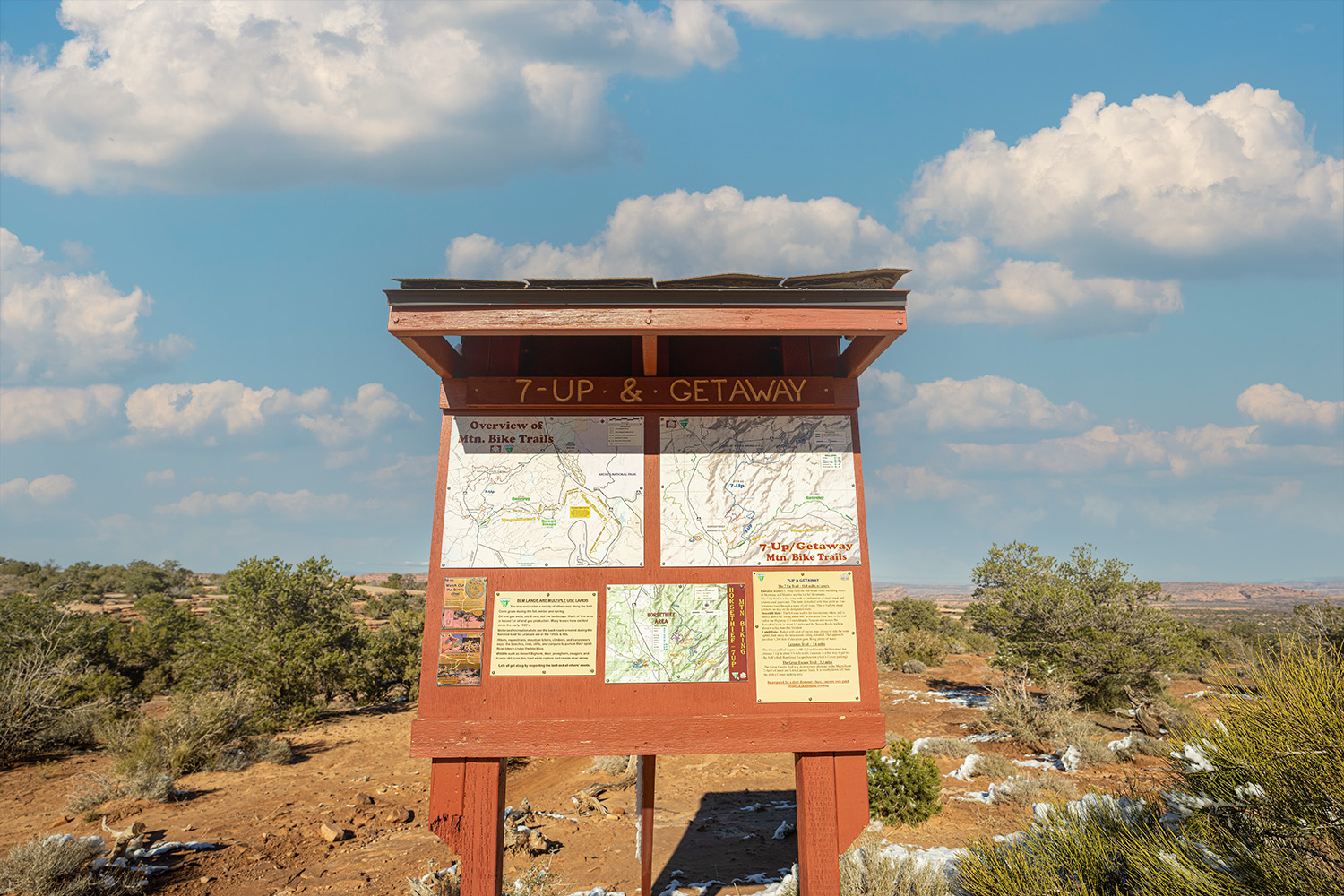 A trailhead map at the trailhead of where these to riders are riding