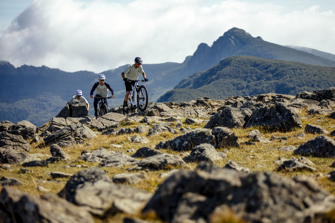 Three mountain bikers riding on stones