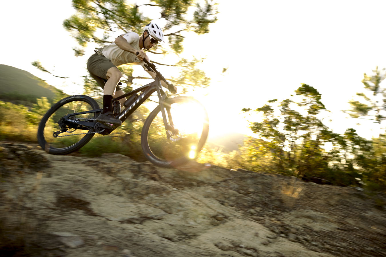 A mountain biker riding a SCOTT Black Bike in a white helmet