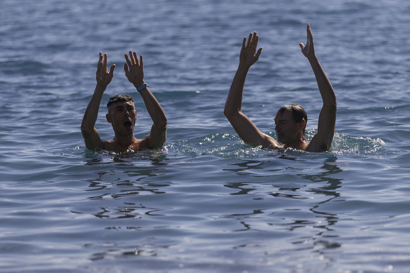 Two men in the water with arms in the air