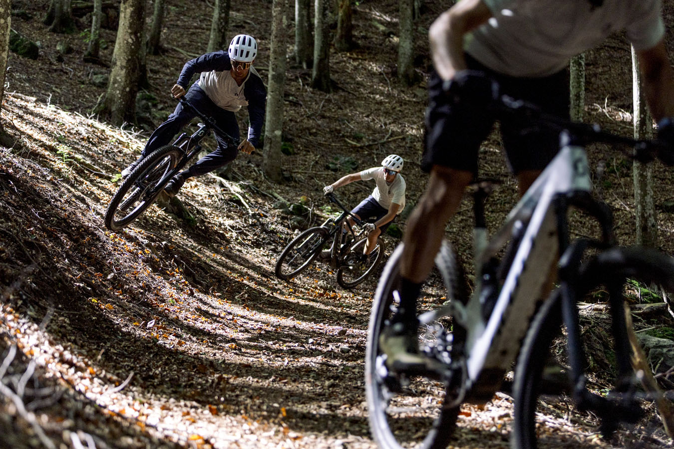 Close up on three mountain bikers riding in the forest