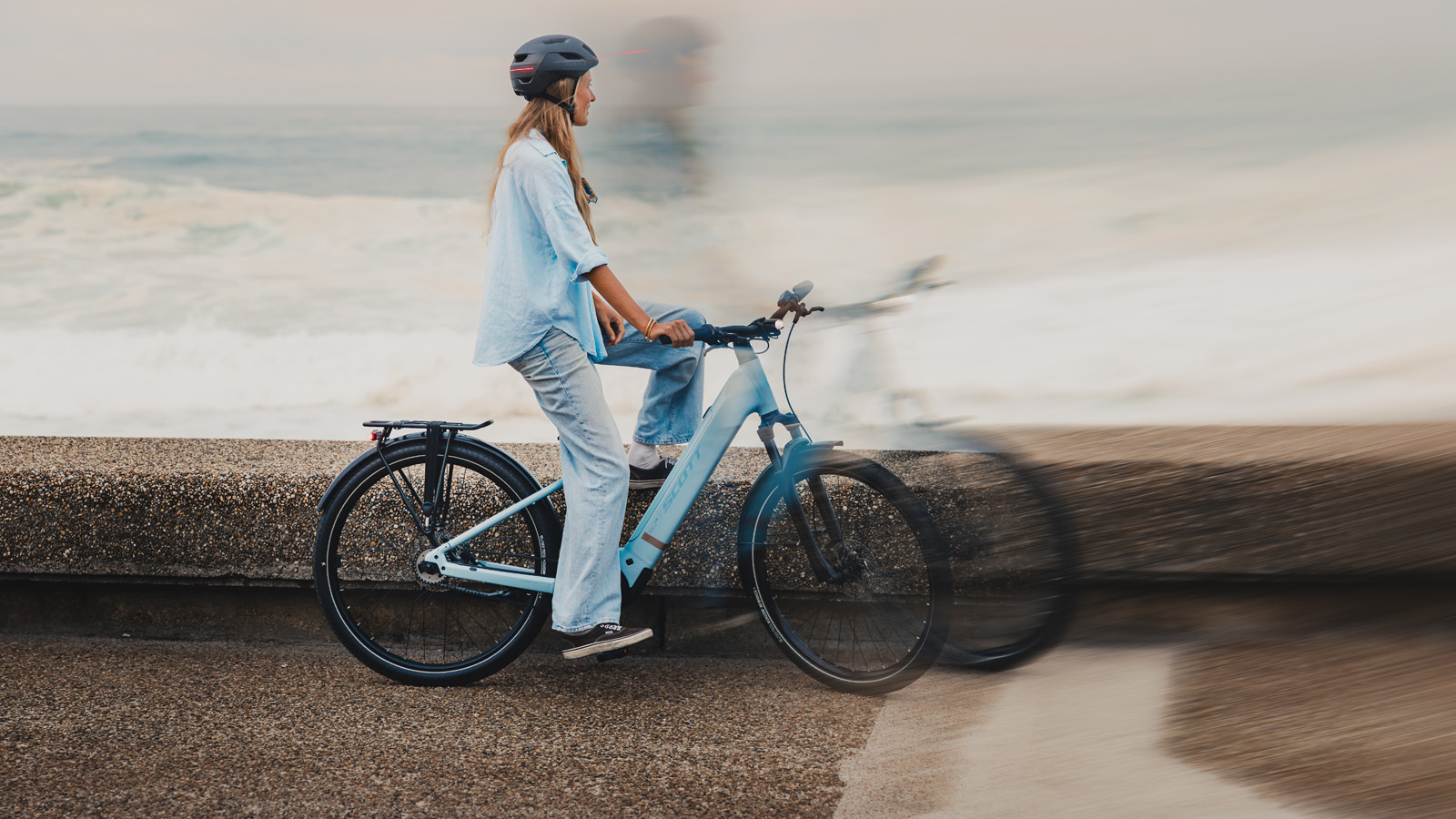 Woman sitting on her bike while watching the ocean.