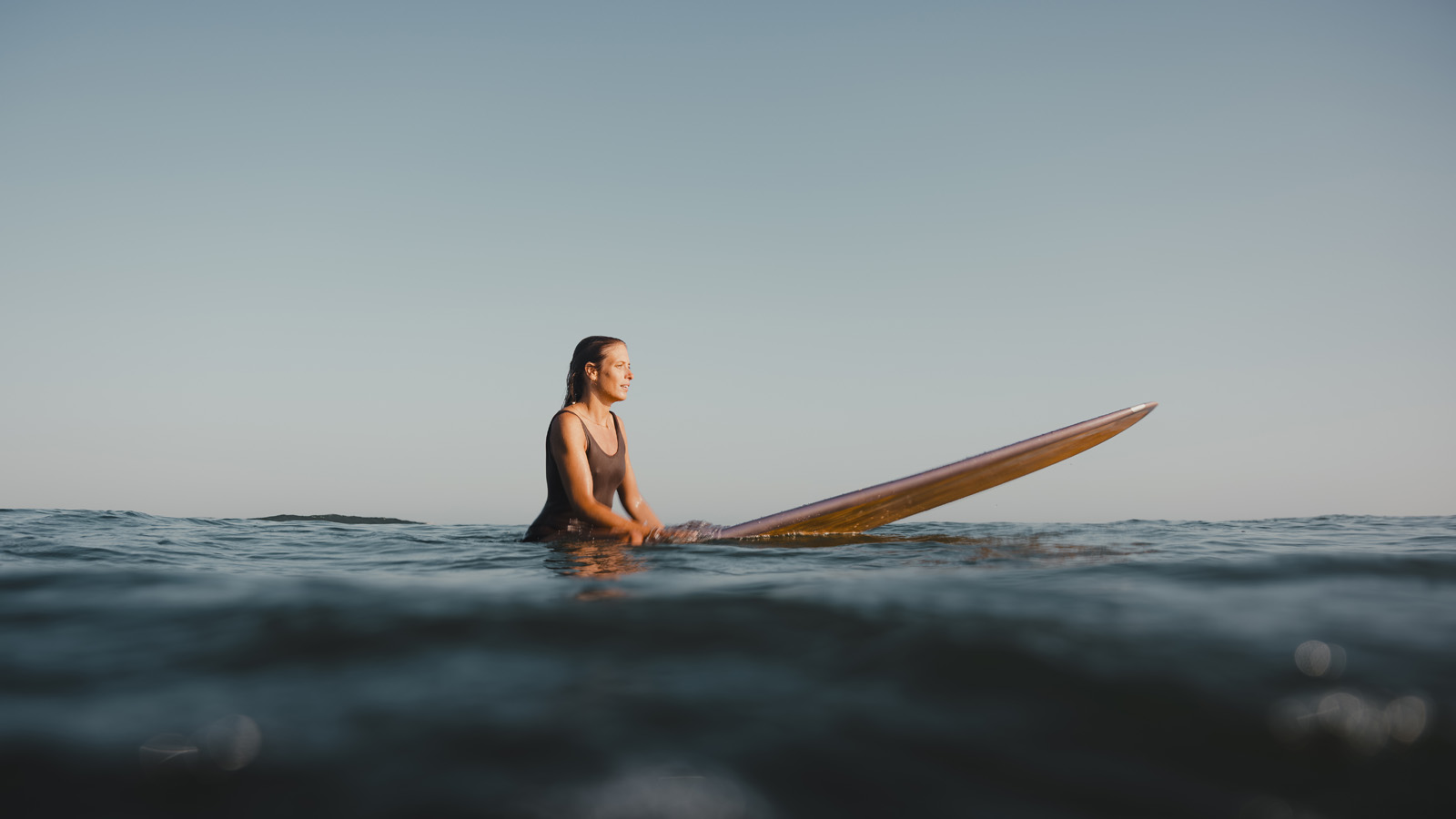 Woman sitting on her surfboard in the ocean