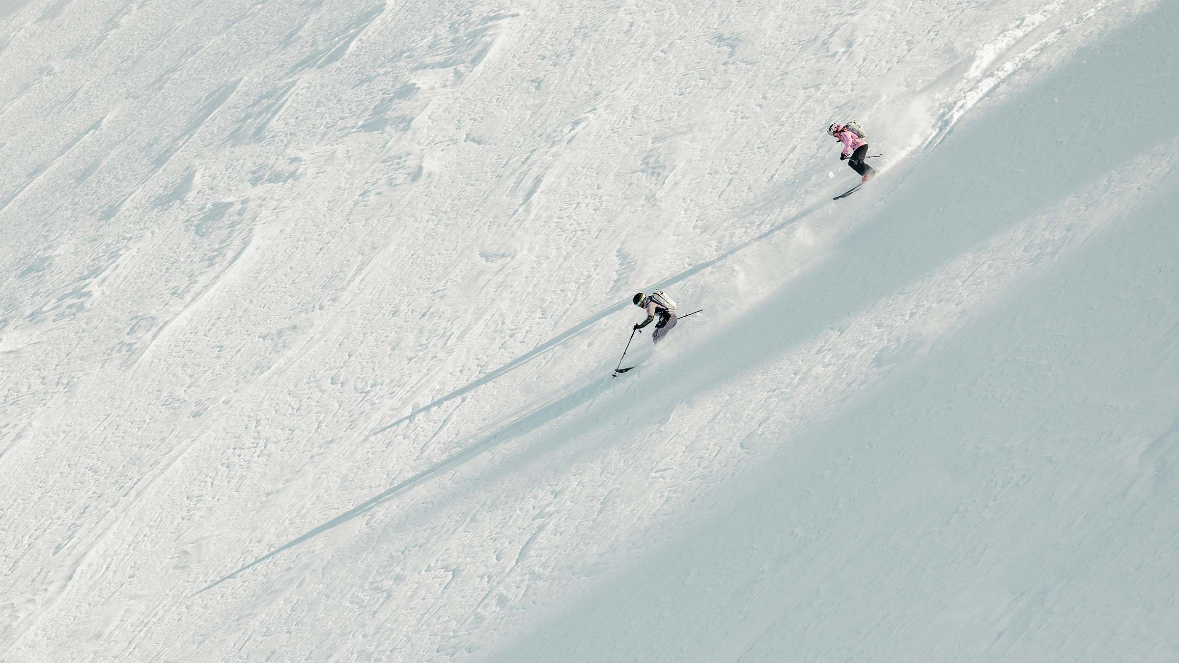Two people on a backcountry tour skiing downhill in SCOTT gear