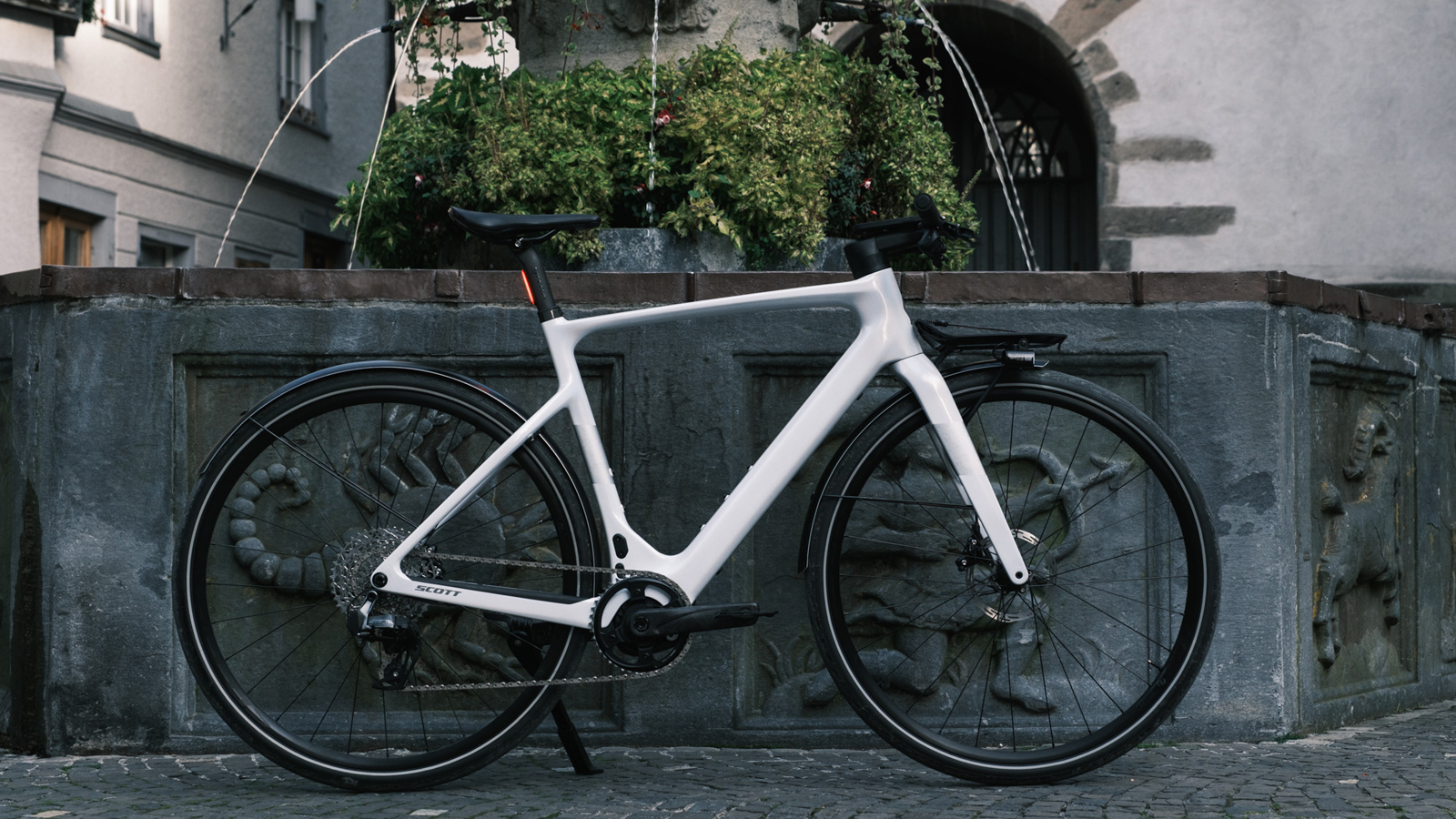 SCOTT Silence eRIDE  positioned in front of a decorative stone fountain in an urban setting.