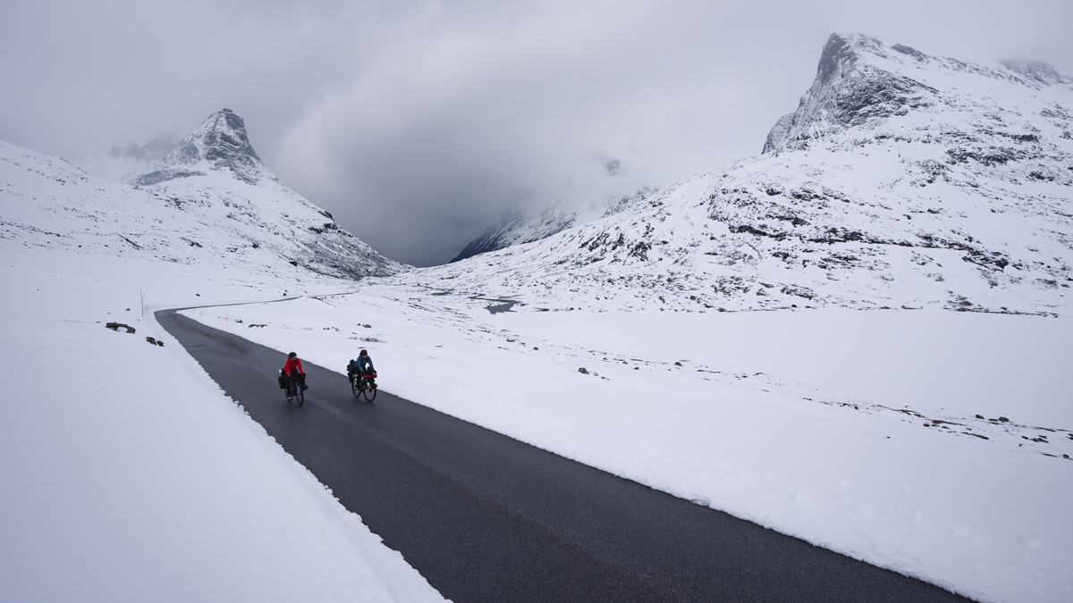 Women riding bike in the road with snow mountains
