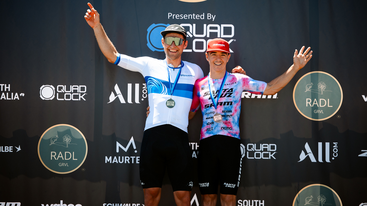 Cameron Jones posing after a race with a medal around his neck and a man next to him