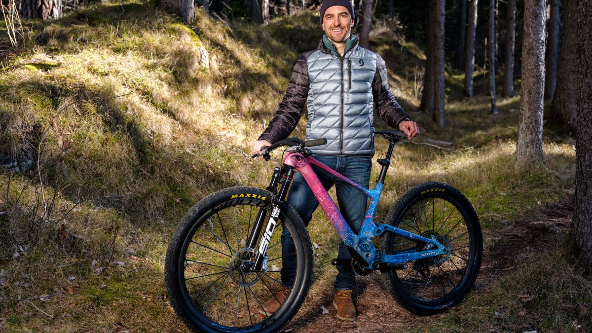 Nino Schurter standing behin bike painted by artist Lionel Smit