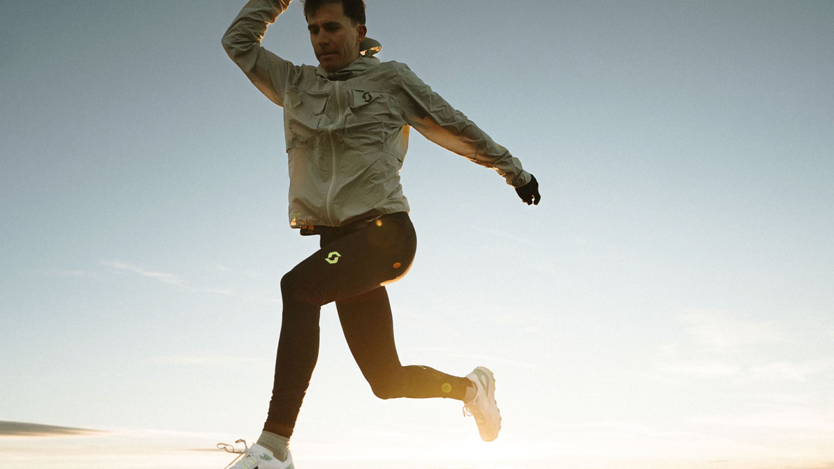 Man wearing Scott RC Run men's windbreaker jacket and running tights for cold weather trail running.