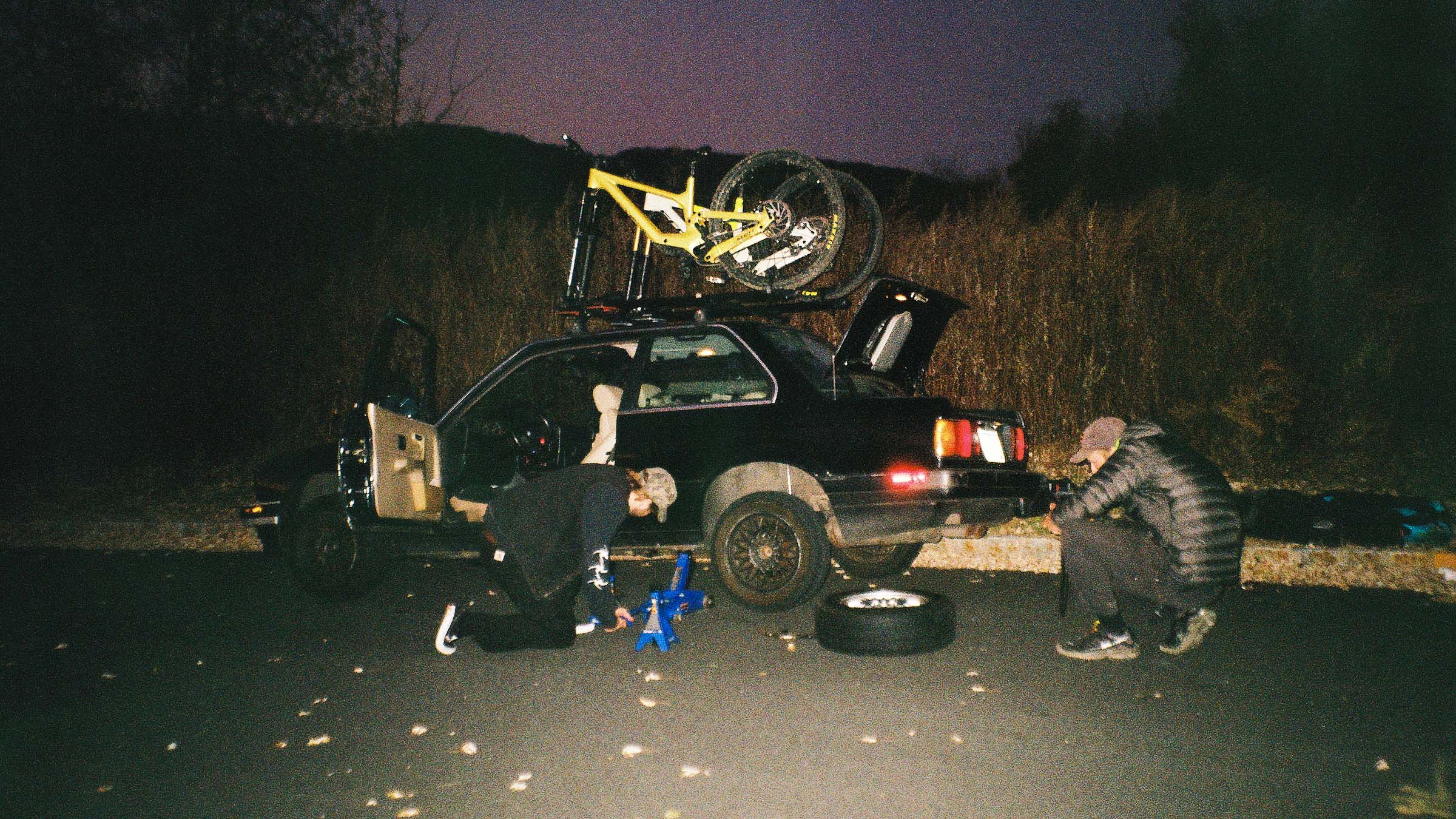 Drew Boxold, Tanner Stephens, and Wiley Kaupas fixing a flat tire on the BMW e30