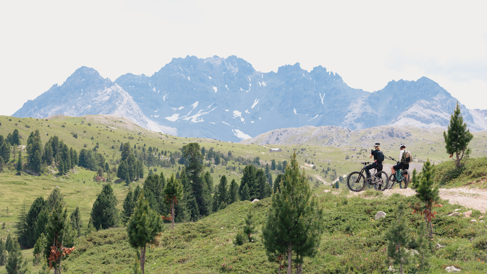 Two women sitting on a bikes and watching a mountain scenery
