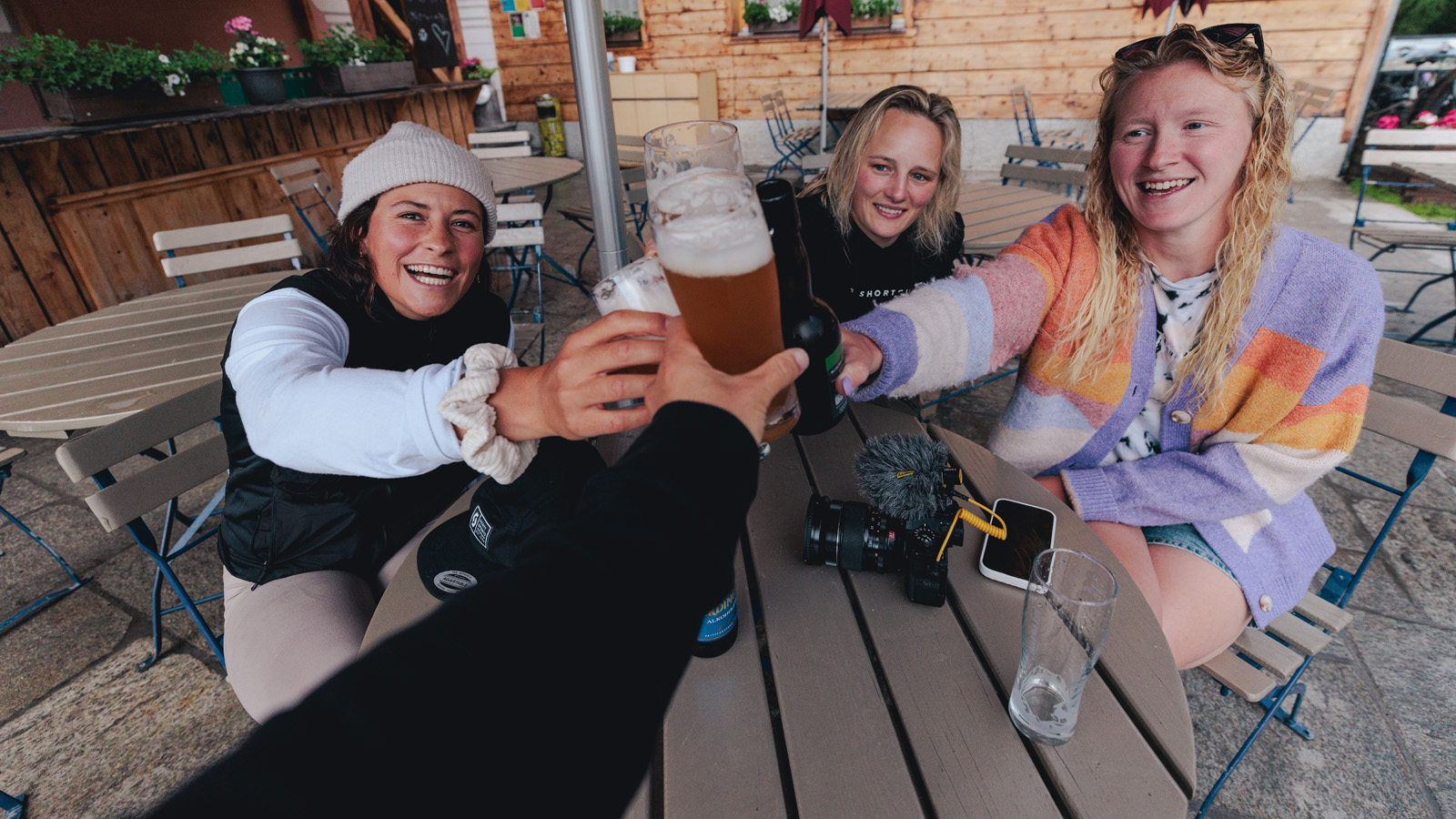 Four women in a terrace and cheering with beers