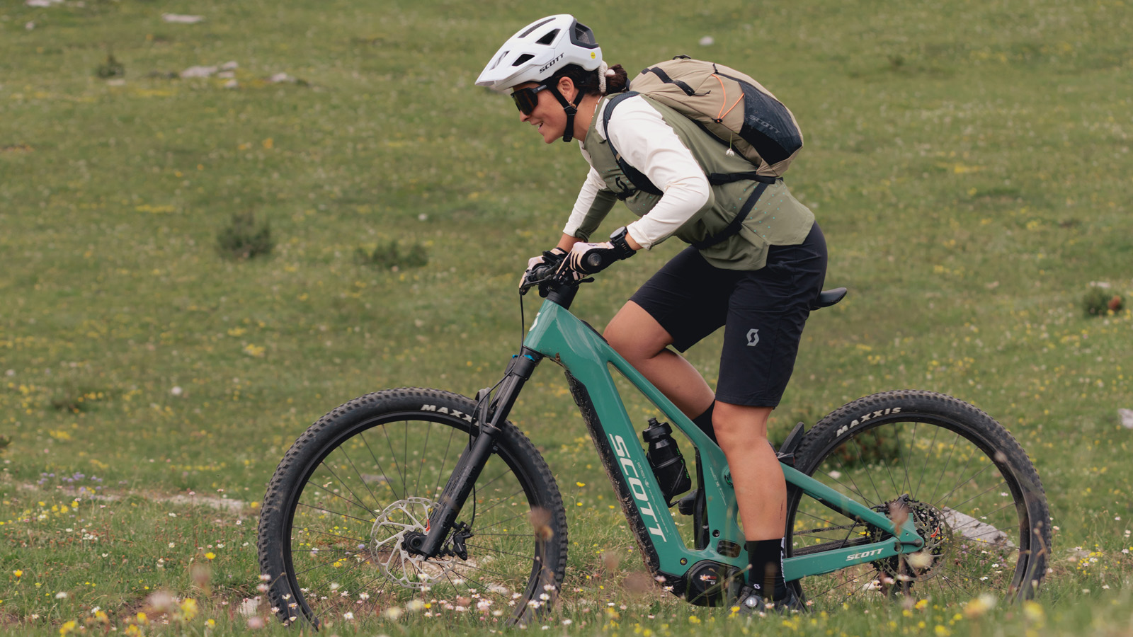 Women riding a bike and smilinh she wears full SCOTT outfit gear