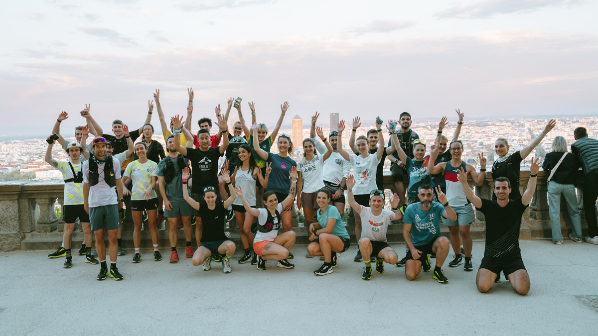 Bunch of people waring running SCOTT gears gathered and posing with arms in the air