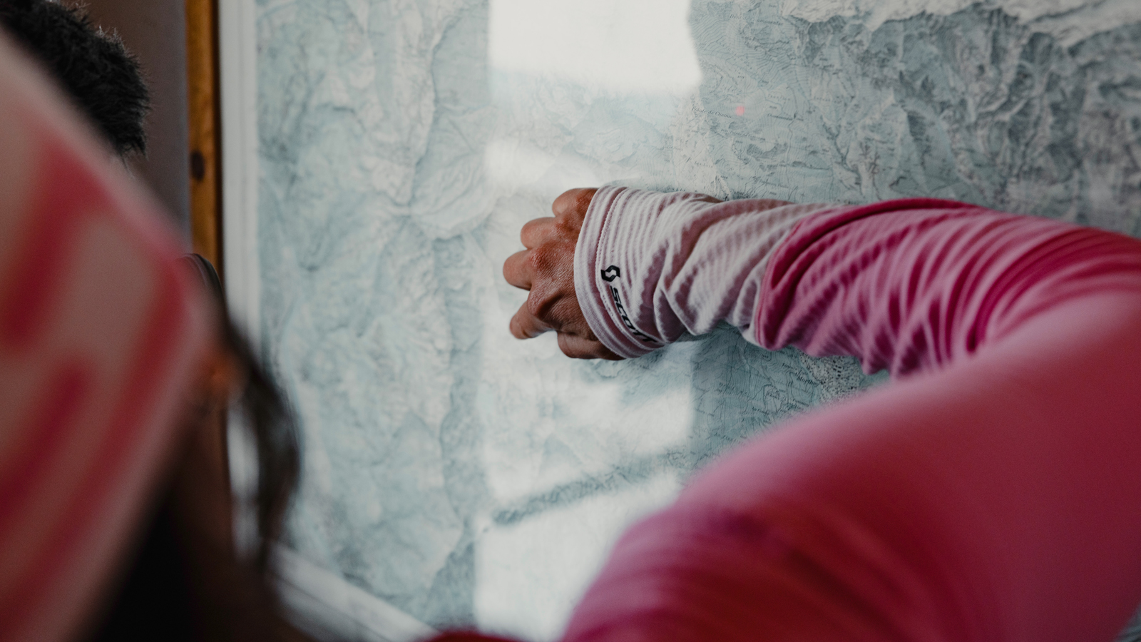 Sabine Schipflinger showing a map with her finger while wearing a SCOTT shirt pink long sleeve