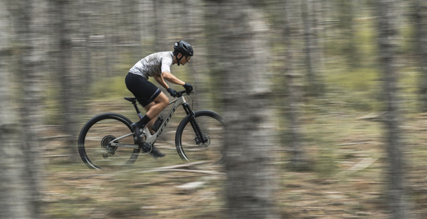 Cyclist in action on a gray Scott Spark RC mountain bike riding through a forest with a speed effect.