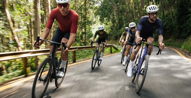 Group of road cyclists wearing Scot aerodynamic jerseys during a training session in the forest.